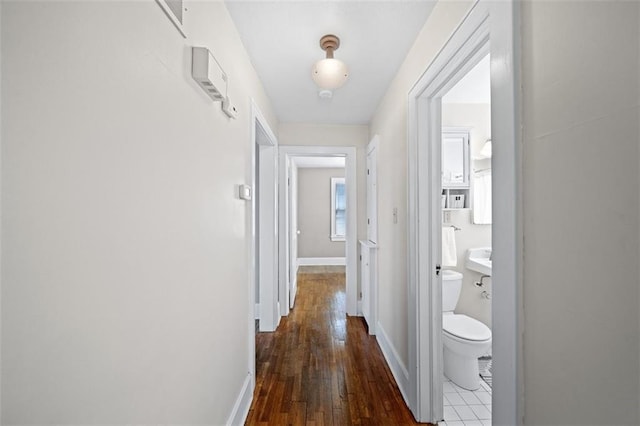 corridor with dark wood-type flooring and baseboards