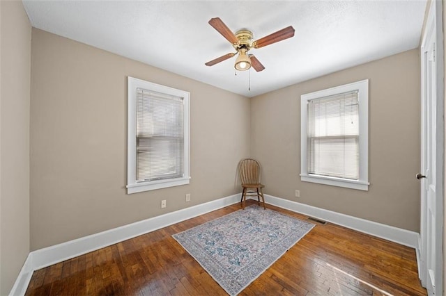 sitting room with ceiling fan, visible vents, baseboards, and dark wood finished floors