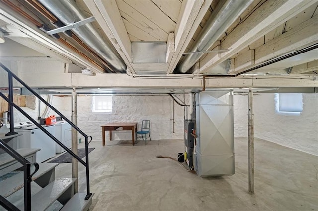 below grade area featuring washing machine and clothes dryer, stairway, and heating unit