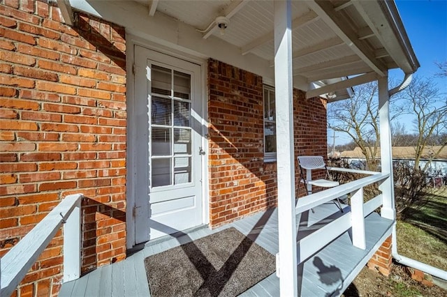 property entrance featuring covered porch and brick siding