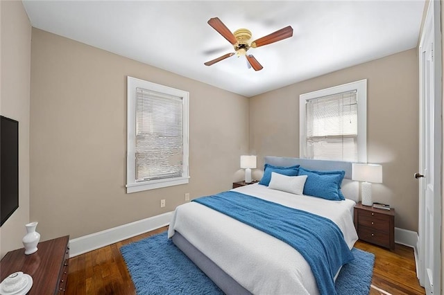 bedroom with a ceiling fan, baseboards, and dark wood-type flooring