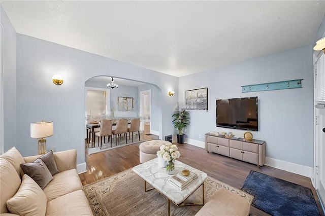 living area with a chandelier, arched walkways, baseboards, and wood finished floors