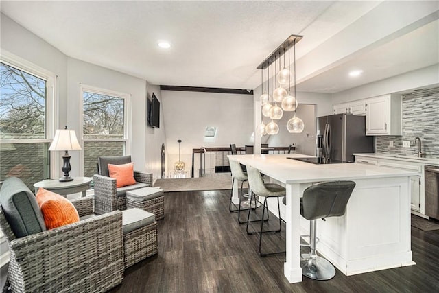 kitchen with hanging light fixtures, a kitchen island, appliances with stainless steel finishes, and white cabinets