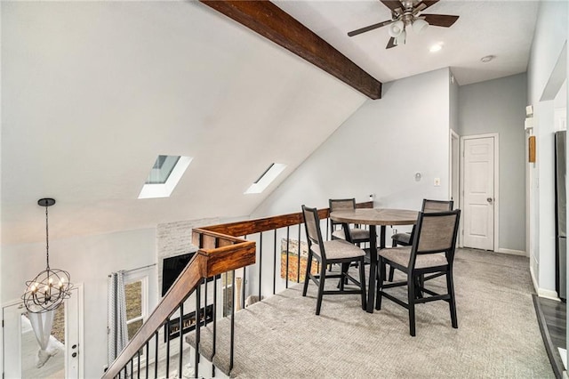 dining room featuring lofted ceiling with skylight and ceiling fan with notable chandelier