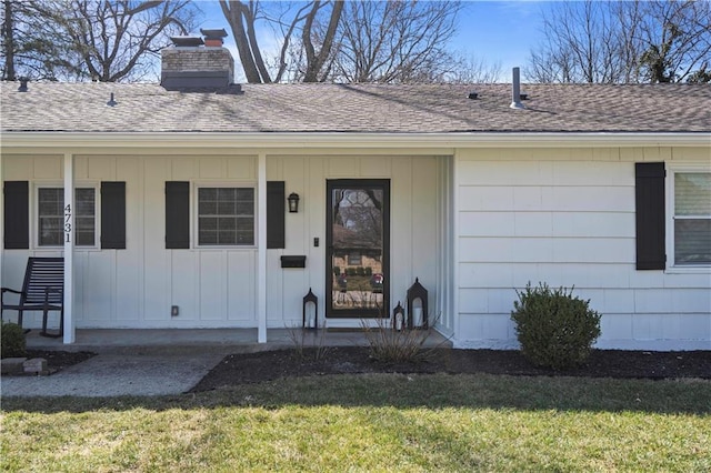 entrance to property with a lawn, board and batten siding, a chimney, and roof with shingles