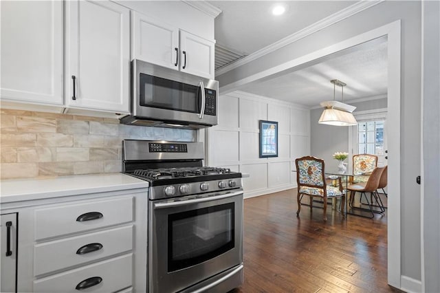 kitchen with backsplash, dark wood-type flooring, ornamental molding, appliances with stainless steel finishes, and white cabinetry