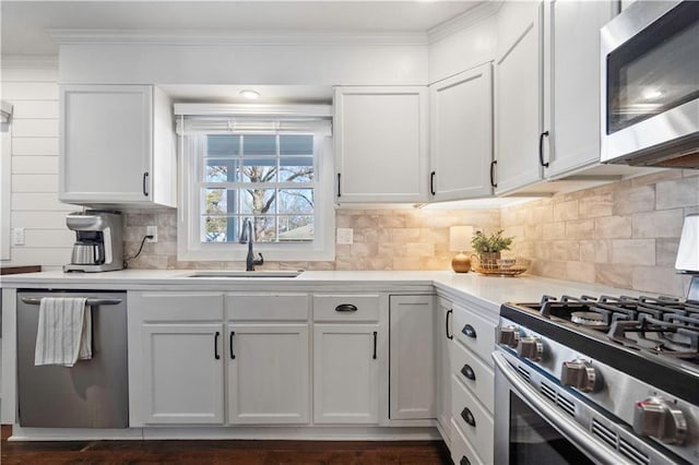 kitchen with a sink, crown molding, white cabinets, and stainless steel appliances