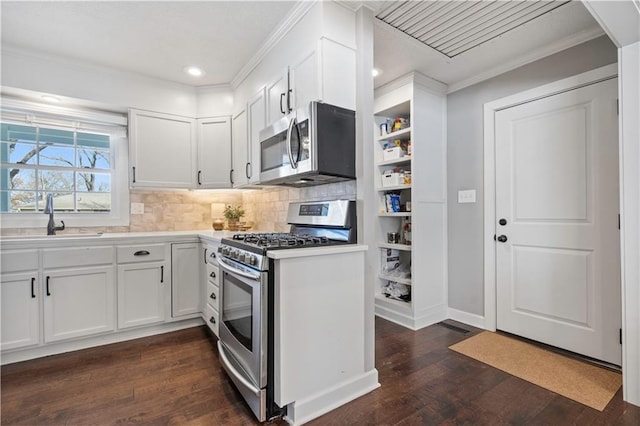 kitchen with crown molding, dark wood finished floors, white cabinets, stainless steel appliances, and a sink