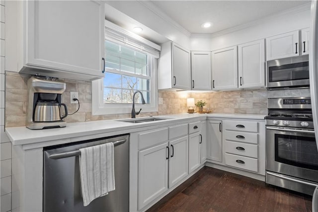 kitchen featuring a sink, stainless steel appliances, light countertops, white cabinets, and dark wood-type flooring