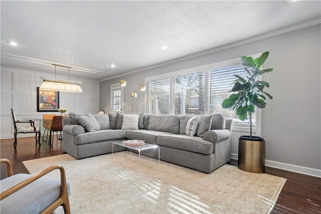 living room featuring baseboards, a textured ceiling, crown molding, and dark wood-type flooring