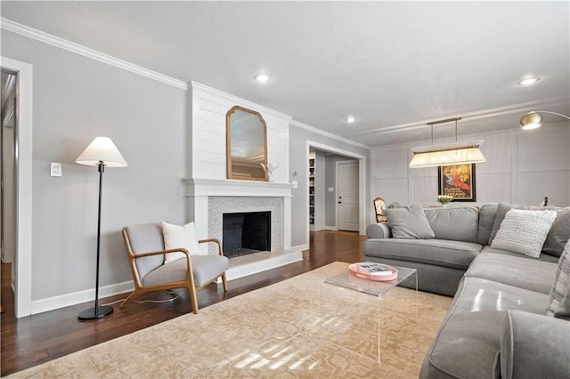 living area featuring a fireplace with raised hearth, a textured ceiling, wood finished floors, crown molding, and baseboards