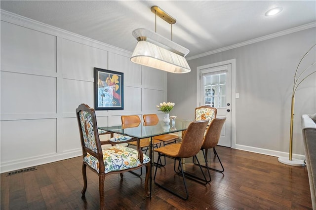 dining space featuring dark wood finished floors, a decorative wall, visible vents, and ornamental molding