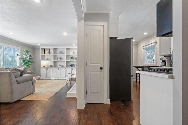 kitchen with white cabinetry, crown molding, dark wood-style flooring, and freestanding refrigerator