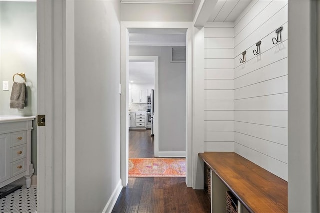 mudroom featuring dark wood-type flooring, visible vents, and wood walls