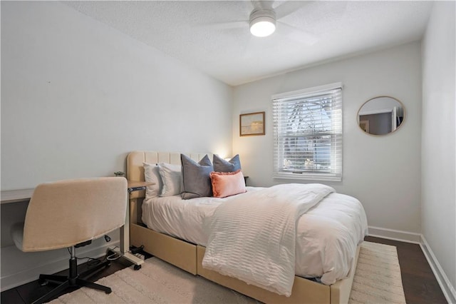 bedroom with a ceiling fan, wood finished floors, baseboards, and a textured ceiling