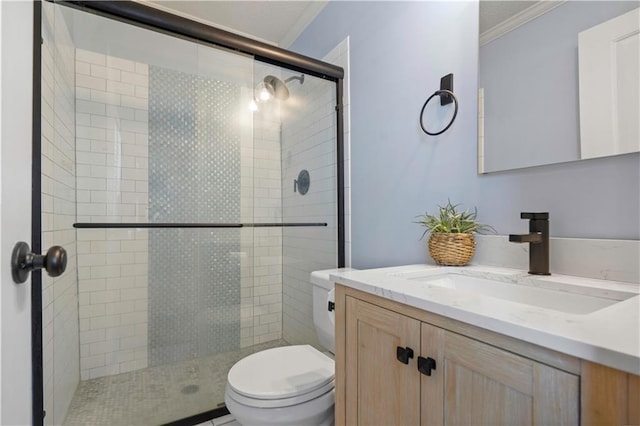 bathroom featuring vanity, a shower stall, toilet, and ornamental molding