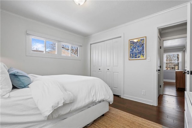 bedroom with a closet, baseboards, ornamental molding, and hardwood / wood-style flooring