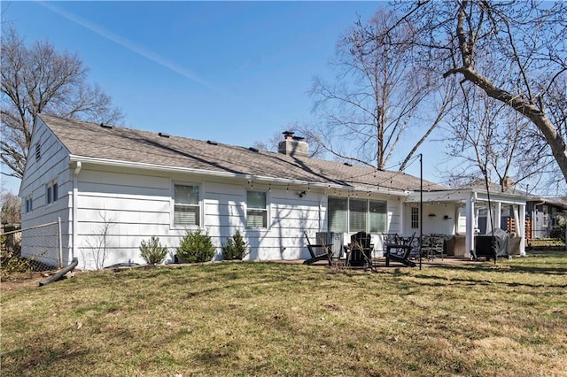 back of house with a lawn, a chimney, and a patio