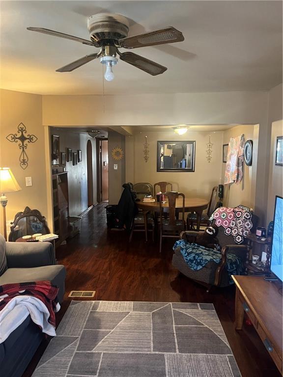 living room with dark wood-type flooring and ceiling fan