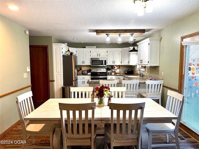 dining room featuring dark hardwood / wood-style flooring, sink, and a textured ceiling