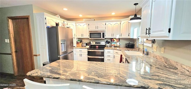 kitchen featuring sink, white cabinetry, kitchen peninsula, stone counters, and stainless steel appliances