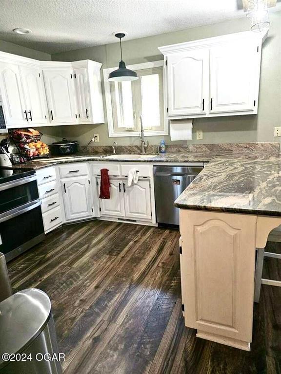 kitchen featuring appliances with stainless steel finishes, a textured ceiling, hanging light fixtures, and white cabinets