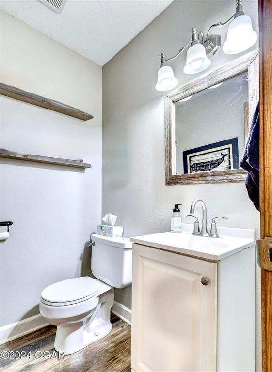 bathroom with wood-type flooring, toilet, and vanity