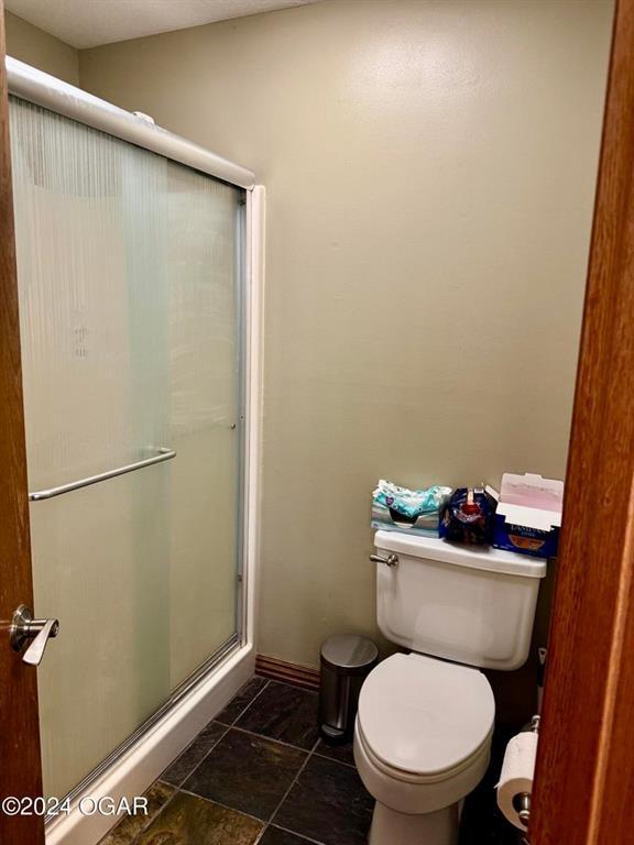 bathroom with toilet and a shower with shower door