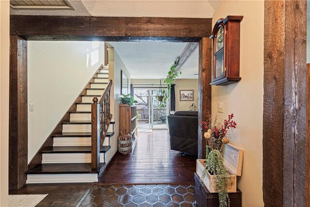 stairs with beamed ceiling, wood-type flooring, and a textured ceiling