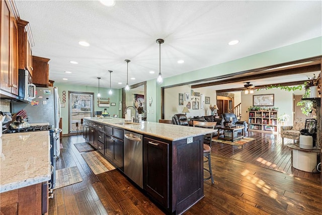 kitchen with a large island, sink, pendant lighting, dark wood-type flooring, and stainless steel appliances