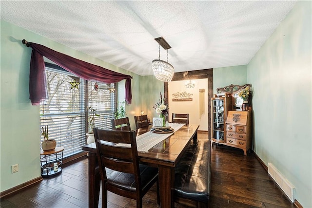 dining room featuring dark hardwood / wood-style flooring, a textured ceiling, and an inviting chandelier