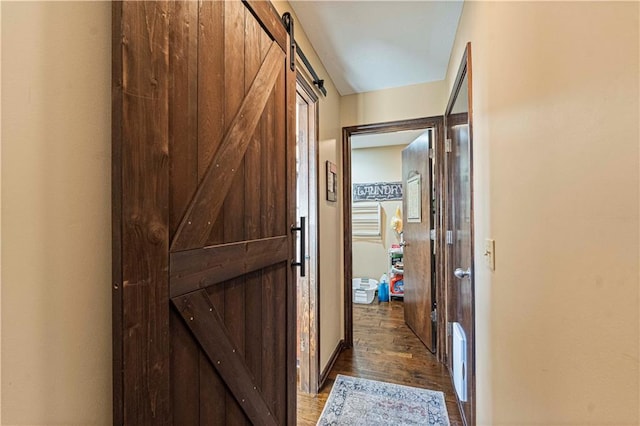 hallway with a barn door and dark hardwood / wood-style flooring