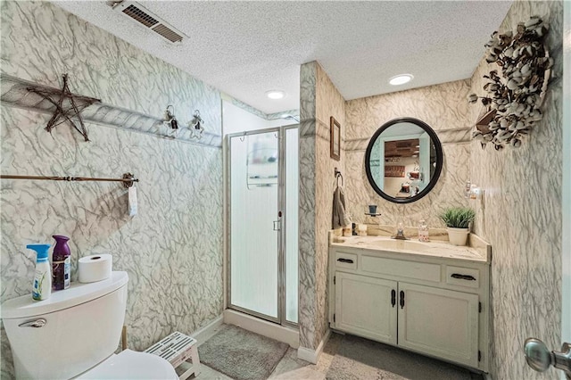 bathroom featuring vanity, toilet, a shower with door, and a textured ceiling