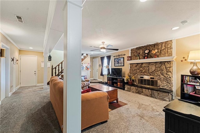 living room featuring crown molding, a fireplace, ceiling fan, and carpet