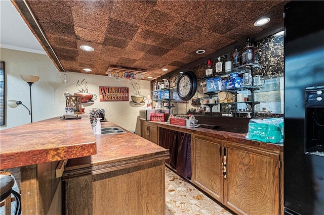 bar featuring ornamental molding, sink, and black refrigerator with ice dispenser