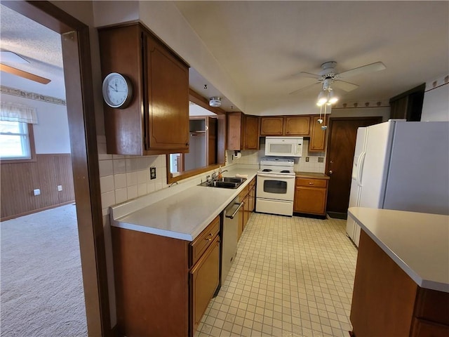 kitchen featuring sink, white appliances, ceiling fan, tasteful backsplash, and wood walls