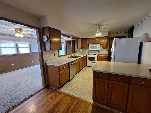 kitchen featuring wooden walls, sink, ceiling fan, light hardwood / wood-style floors, and stainless steel appliances