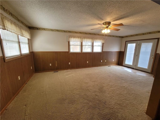 carpeted empty room with ceiling fan, a textured ceiling, and a wealth of natural light