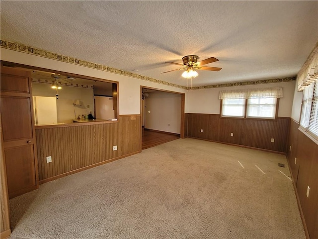 interior space featuring ceiling fan, a textured ceiling, and wood walls