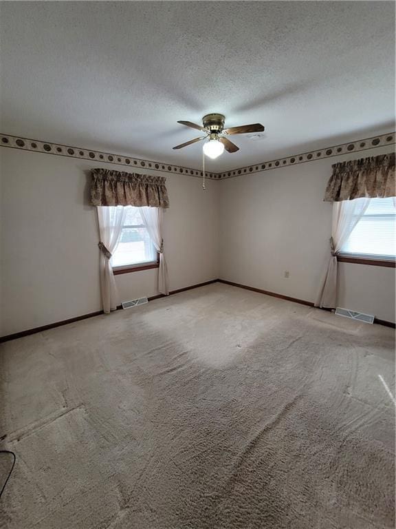 empty room with ceiling fan, carpet, and a textured ceiling