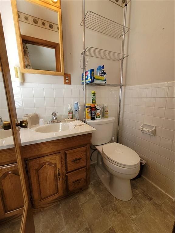 bathroom featuring vanity, toilet, and tile walls