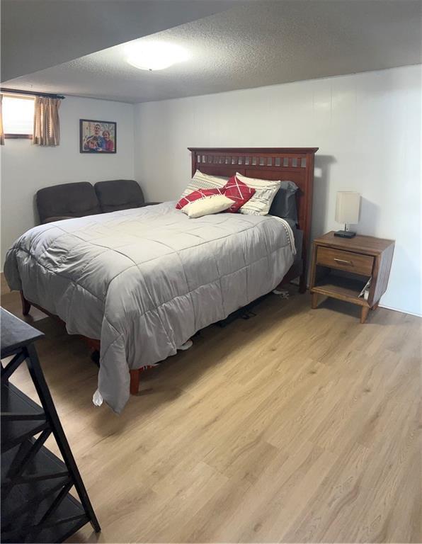 bedroom with a textured ceiling and light wood-type flooring