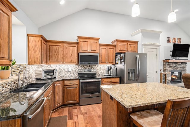 kitchen with appliances with stainless steel finishes, a center island, sink, and hanging light fixtures