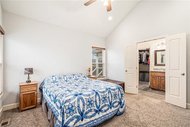 carpeted bedroom featuring ensuite bathroom, high vaulted ceiling, a walk in closet, ceiling fan, and a closet