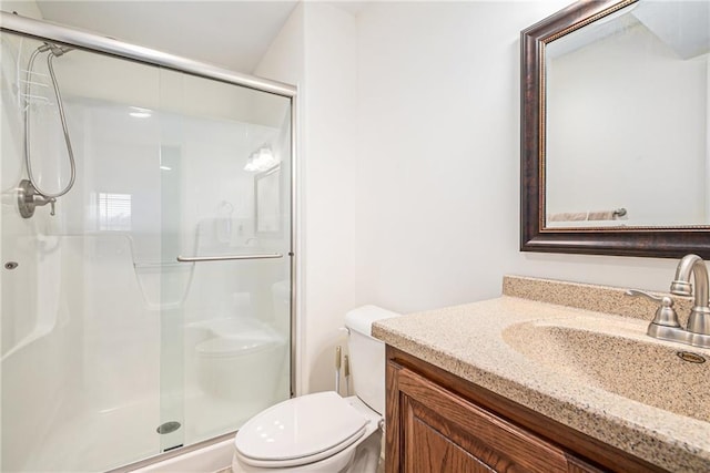 bathroom featuring vanity, toilet, and a shower with shower door