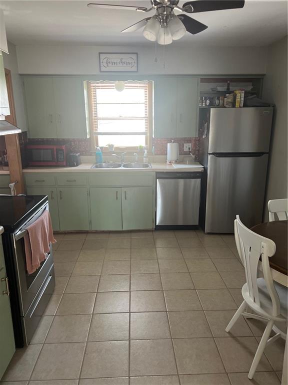 kitchen with backsplash, stainless steel appliances, sink, and light tile patterned floors