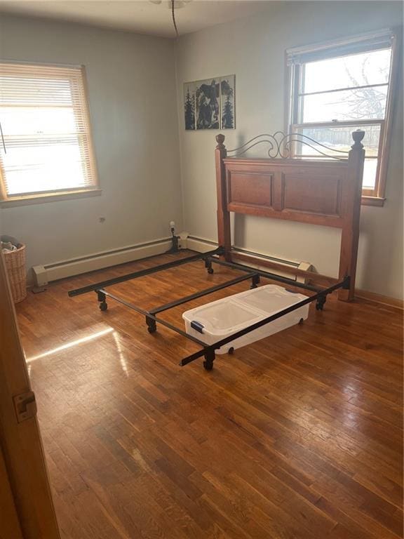 unfurnished bedroom with wood-type flooring and baseboard heating