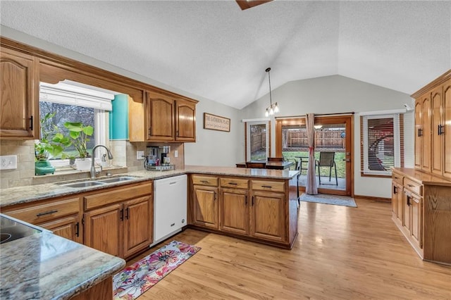 kitchen with white dishwasher, a peninsula, a sink, light wood-type flooring, and brown cabinetry