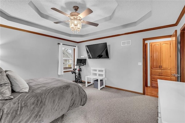 bedroom with baseboards, visible vents, ornamental molding, a tray ceiling, and a textured ceiling