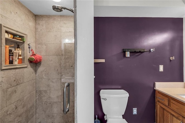 full bath featuring toilet, tiled shower, and vanity